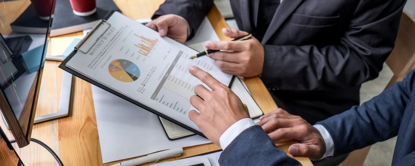Two consultants reviewing procurement paperwork together at a desk